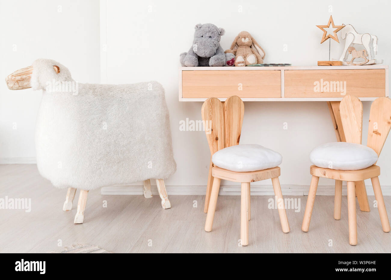 2 Stühle mit Hasenohren im Kinderzimmer, ein Tisch mit Spielzeug und einem großen Schaf Stockfoto