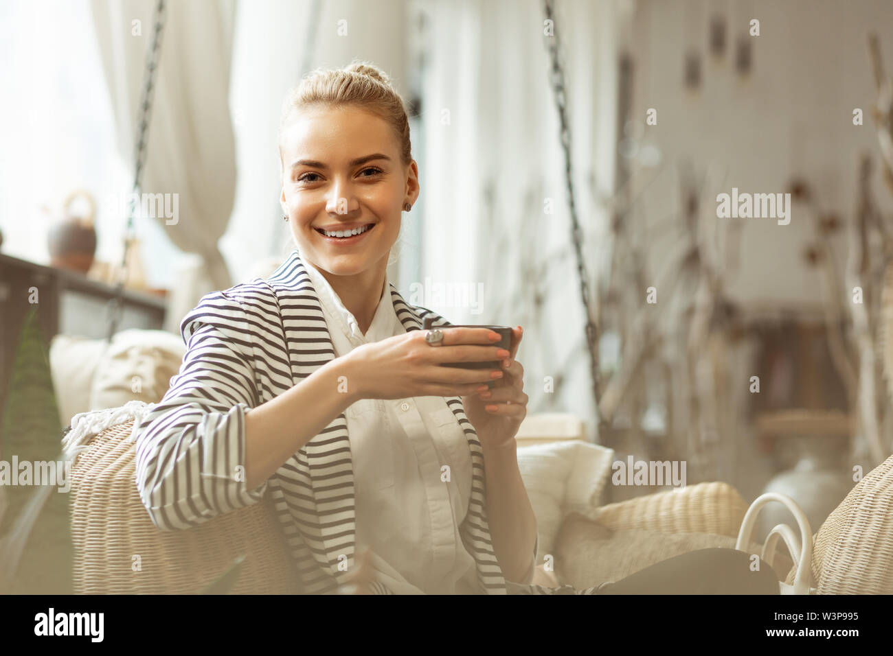 Tee aus einer Teekanne. Neugierig schöne Frau in weißem T-Shirt, Tasse mit Kaffee und lehnte sich auf ein Zurück Stockfoto