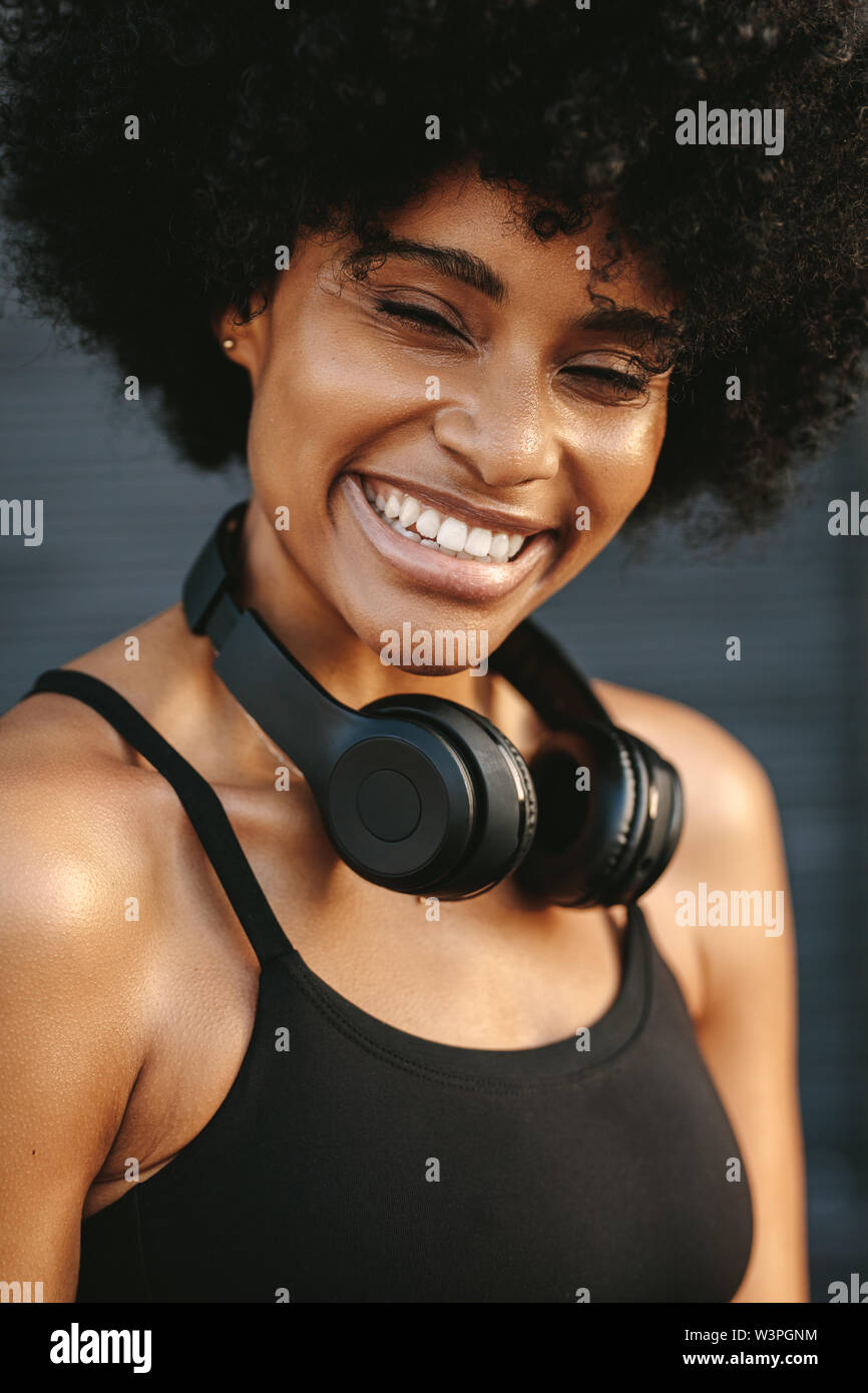 Läuferin lächelnd nach einem Lauf am Morgen. Frau in Fitnessgeräte mit Kopfhörer um den Hals. Stockfoto