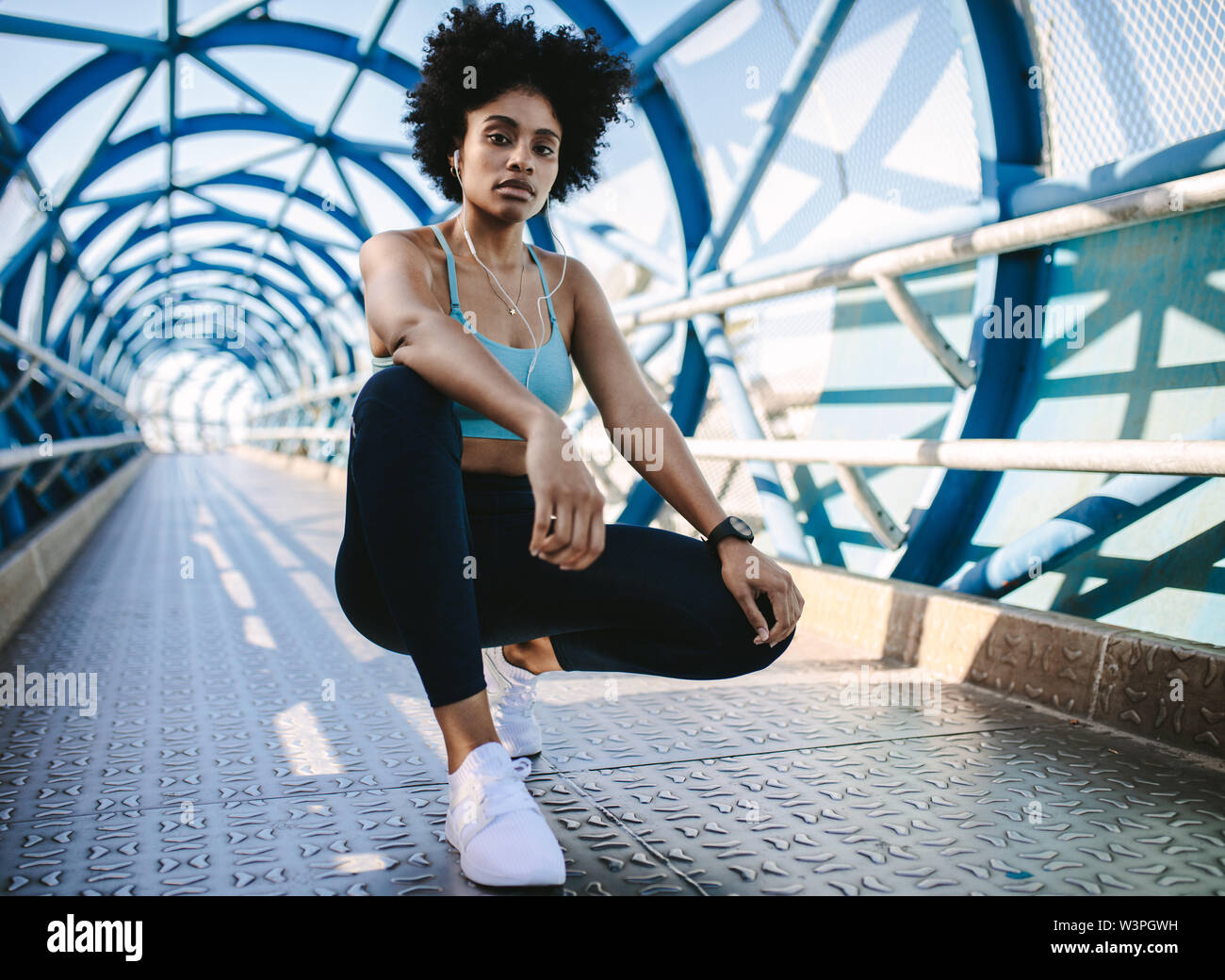 Junge Frau runner Ausruhen nach Lauftraining. Weibliche fitness Modell zusammengekauert auf einer Brücke. Stockfoto