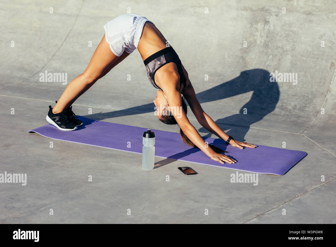 Gesunde Frau Yoga am Morgen. Weibliche in Sportkleidung zu tun stretching Training im Freien, sie übt in den nach unten schauenden Hund yoga dar. Stockfoto