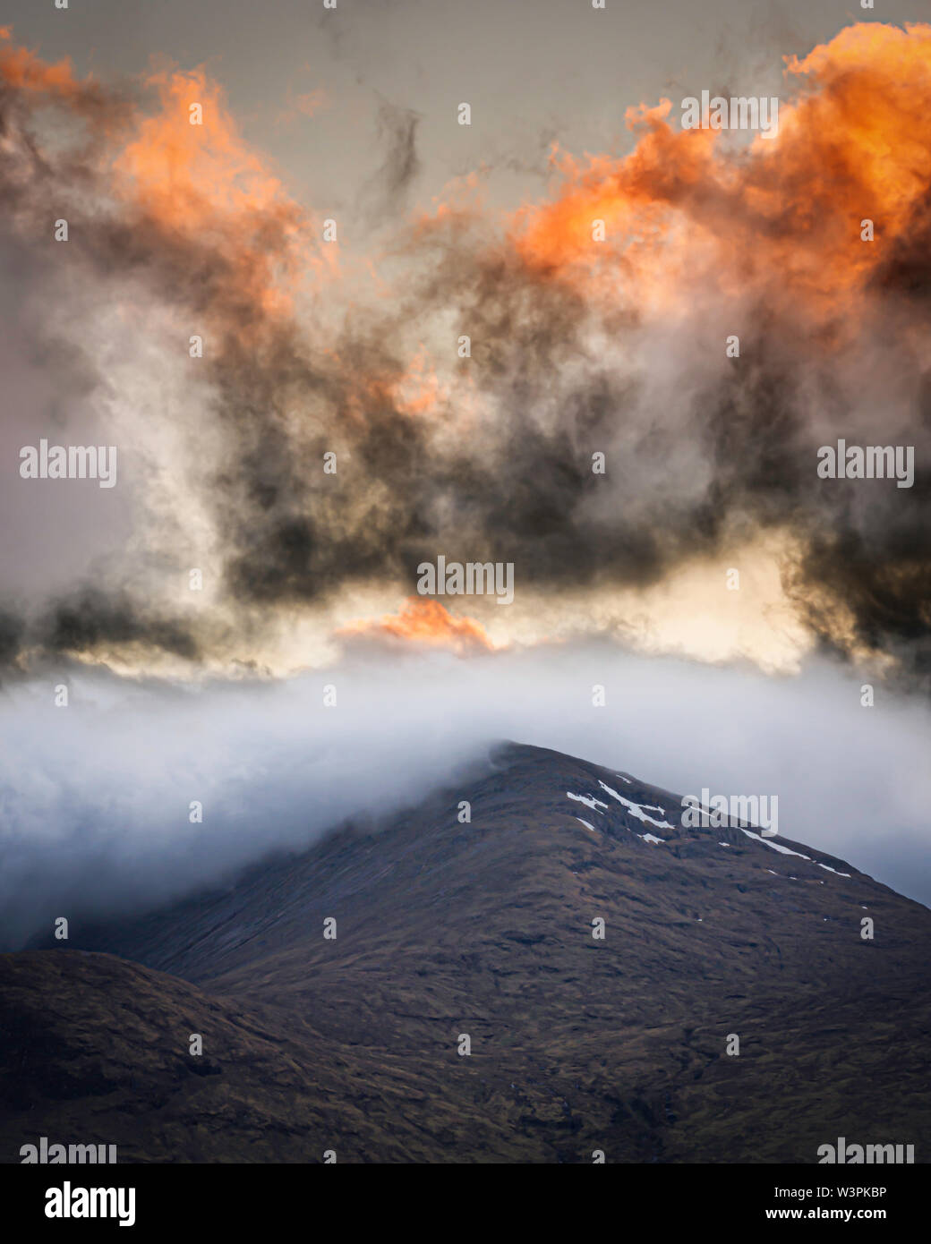 Die untergehende Sonne die Wolken über dem Gipfel im schottischen Hochland. Schönen Sonnenuntergang Szene mit bunten und dramatischen Himmel. Majestic cloudscape. Stockfoto