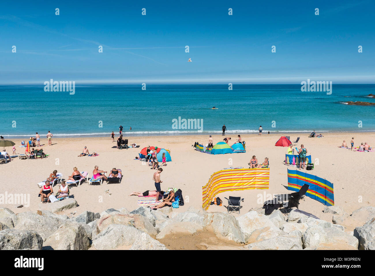Urlauber entspannen und genießen Sie die Sonne, während Sie am Strand von Fistral in Newquay in Cornwall sonnen. Stockfoto