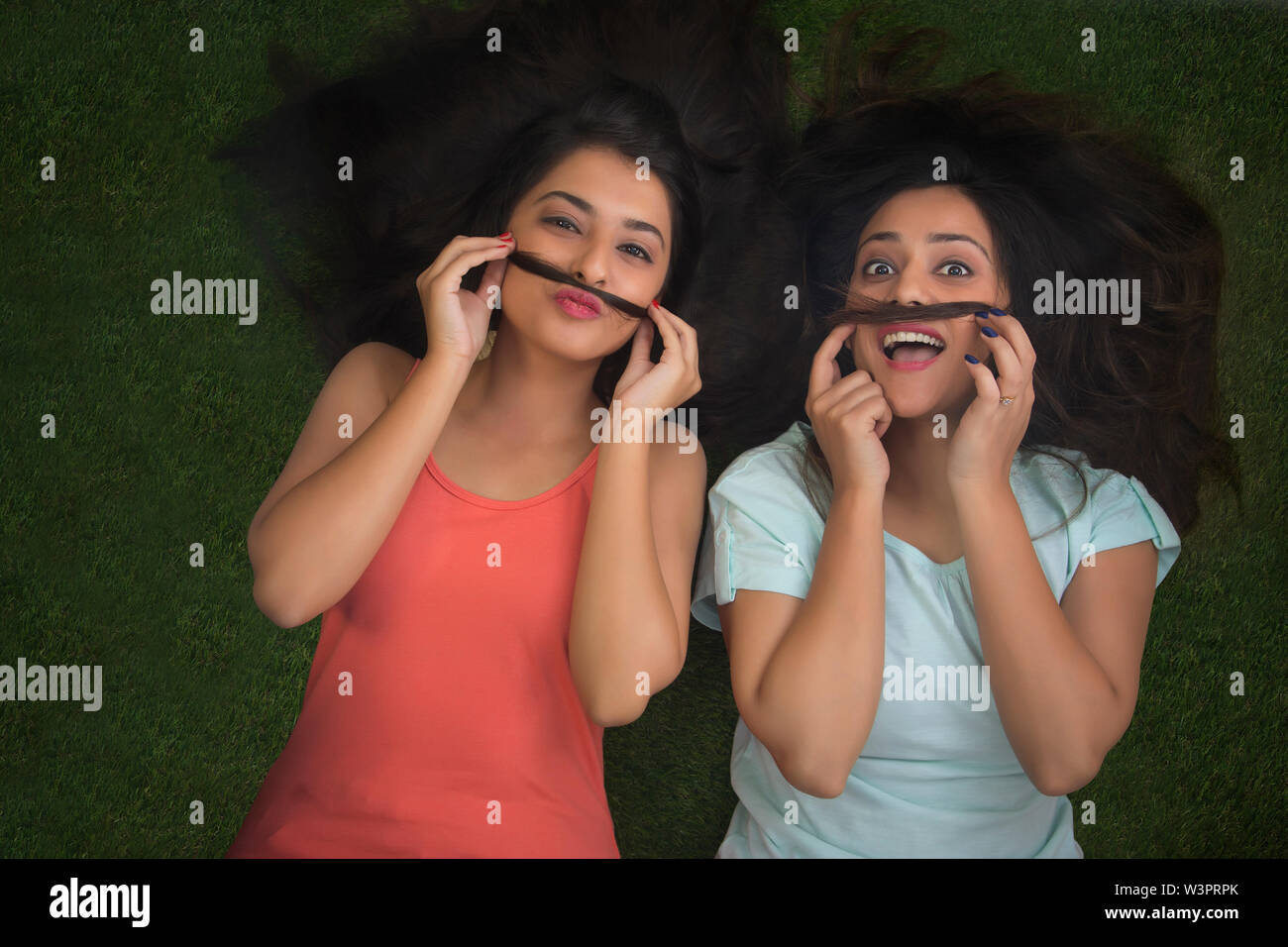 Blick von oben auf die zwei glückliche Jugend Mädchen liegen auf Gras und Schnurrbärte mit ihrem Haar Stockfoto