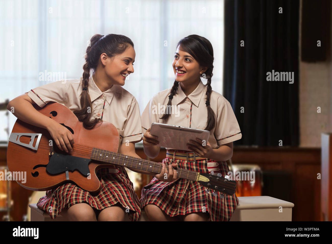 Zwei glückliche Teenager school Mädchen lernen Gitarre im Musikzimmer in der Schule zu spielen Stockfoto