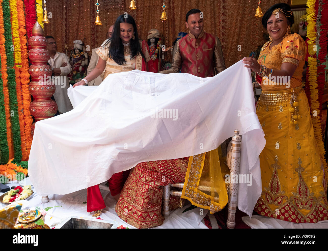 Während eine traditionelle hinduistische Hochzeit Braut & Bräutigam vorübergehend von einem Blatt abgedeckt werden. In einem Tempel in Ozone Park, Queens, New York City. Stockfoto