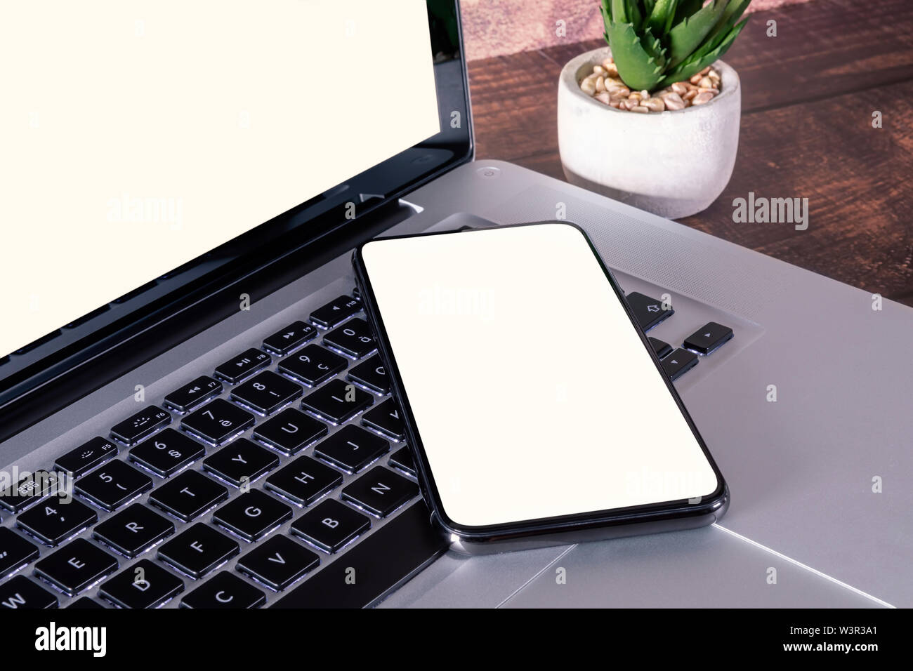 Smartphone weißen leeren Bildschirm auf Laptop Tastatur auf Holztisch mit liefert. Stockfoto