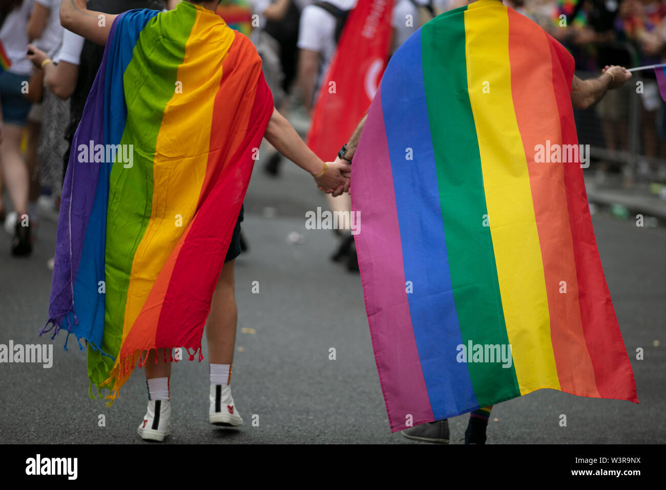 Zwei homosexuelle Männer in Gay Pride flags Hand in Hand mit einander gewickelt Stockfoto
