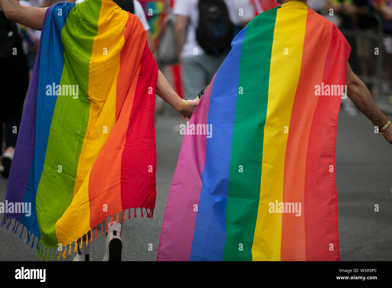 Zwei homosexuelle Männer in Gay Pride flags Hand in Hand mit einander gewickelt Stockfoto