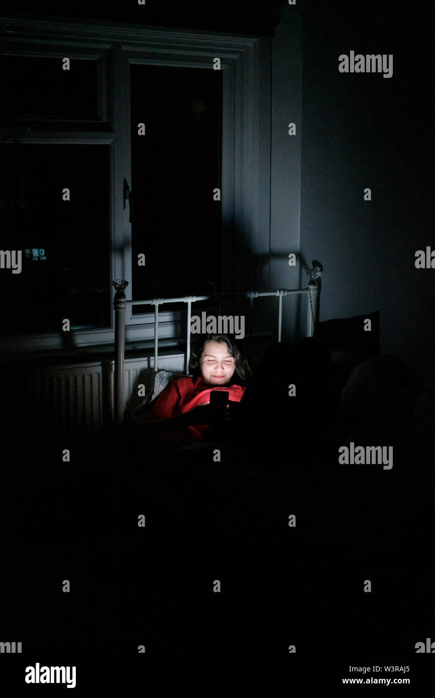 Junges Mädchen, 17 Jahre alt, im Smartphone spät in der Nacht im Bett Stockfoto