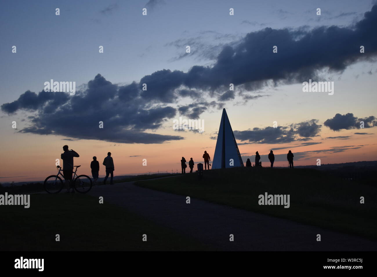 Sonnenaufgang auf der Sommersonnenwende auf der Light Pyramide in Campbell Park, Milton Keynes. Ein Dutzend Leute (nicht identifizierbaren) sind den Sonnenaufgang. Stockfoto