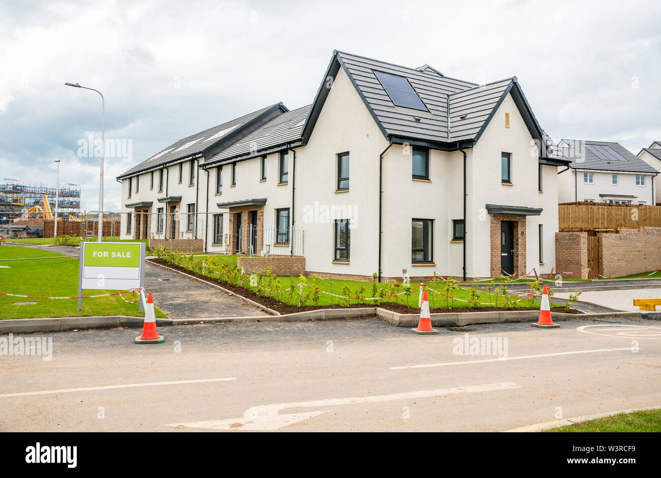 Neue Häuser für Verkauf in einer Wohnsiedlung in Schottland an einem bewölkten Sommertag. Alle Häuser haben Solarzellen auf dem Dach. Stockfoto