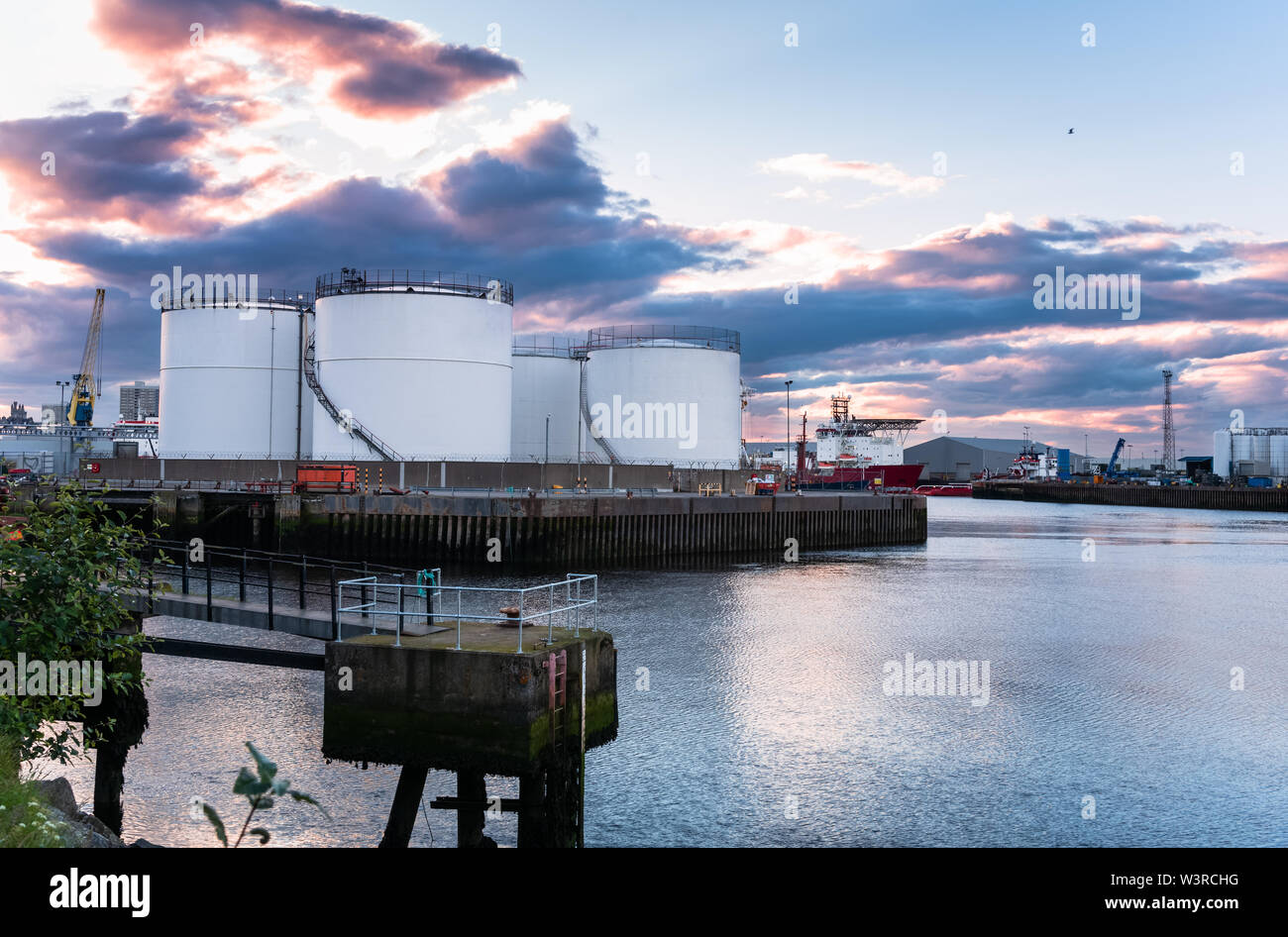 Öltanks auf einem Pier in einem industriehafen. Dramatische bunte Himmel in der Abenddämmerung. Stockfoto