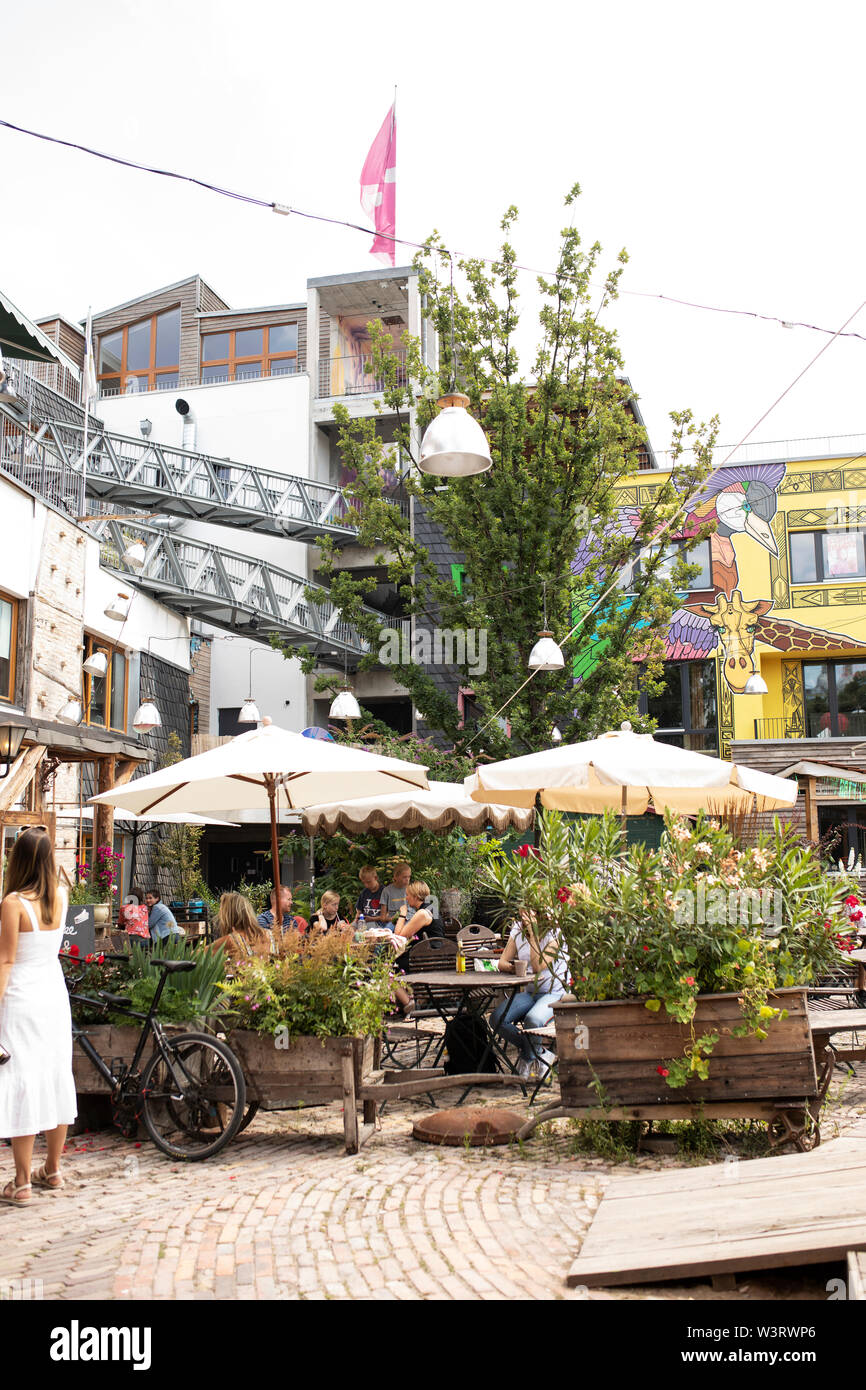 Menschen essen im Freien am Holzmarkt in Berlin, Deutschland, ein kultureller Ort für Veranstaltungen und Künstler mit Studio-Raum und Restaurants. Stockfoto