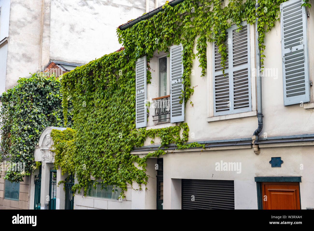 Haus mit grünen Reben an der Wand und Rollläden in Paris, Frankreich Stockfoto