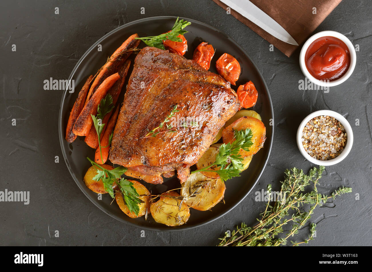 Gebackenes Schweinefleisch, gebratenen Kartoffeln und Karotten auf einer Platte, Ansicht von oben Stockfoto