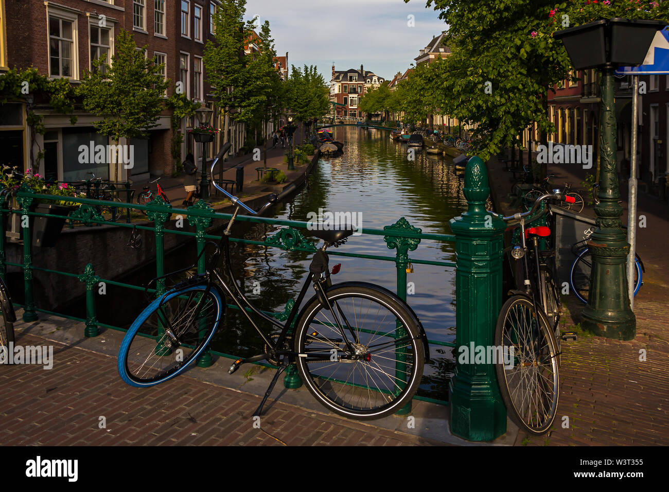 Leiden, Holland, Niederlande, April 18, 2019, Fahrräder auf einer Brücke und entlang einer Straße geparkt, Canal in Leiden Altstadt. Blumen in einem parterres, Boote Stockfoto