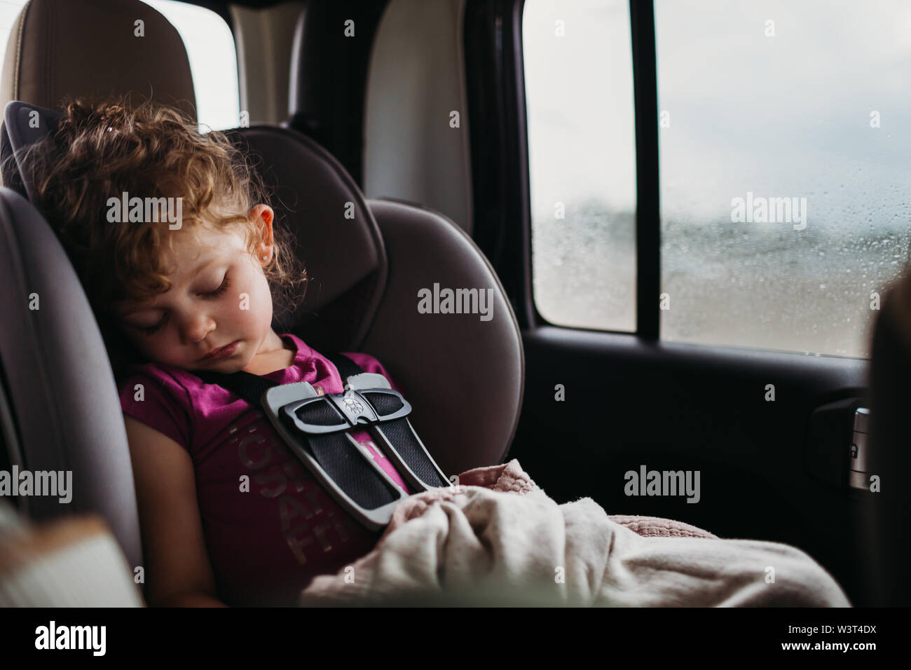Junge Mädchen schlafen im Auto Sitz, während es regnet draußen Stockfoto