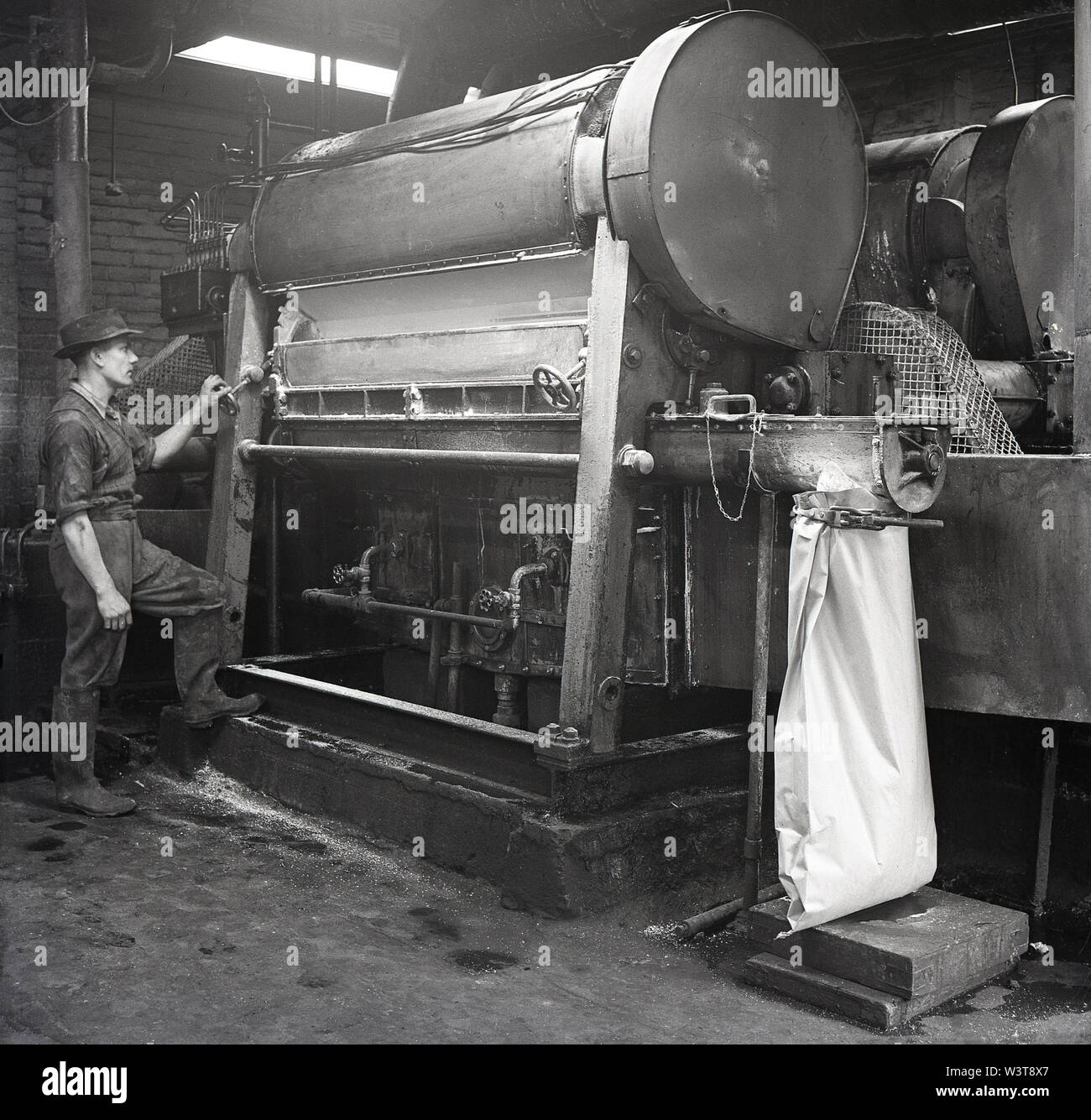 1950, historische, männliche operativen Arbeiten an Maschinen in einer Fabrik, zu der Batterie stets bereit, Forest Road, Walthamstow, London, England, UK. Stockfoto