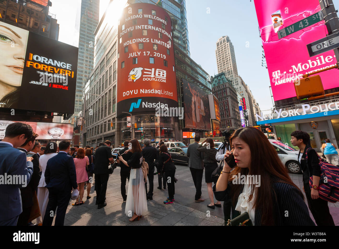 Mitarbeiter mit ihren Familien und Freunden sammeln an der riesigen Bildschirm an der Nasdaq Börse in Times Square in New York für das Debüt des DouYu International Holdings Ltd. Börsengang am Mittwoch, 17. Juli 2019. DouYu ist die größte live-Streaming Plattform in China und wird von Tencent Holdings Ltd. unterstützt die Bewertung der Unternehmen bei $ 3,73 Mrd. ist es die größte chinesische IPO im Jahr 2019. (© Richard B. Levine) Stockfoto