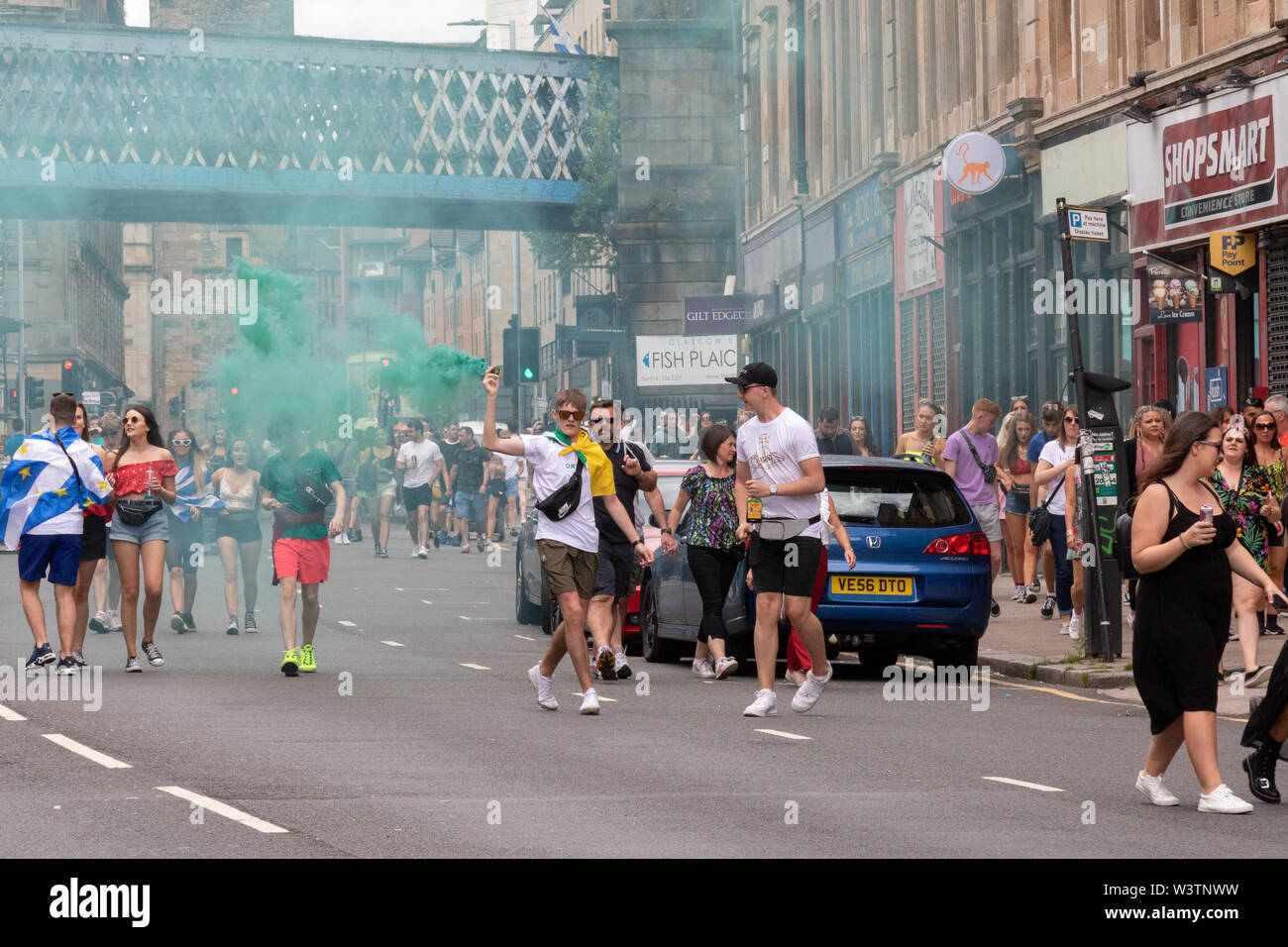 Ein Mann setzt sich ein grüner Rauch flare auf Glasgow's Saltmarket während der 2019 TRNSMT Festival Stockfoto