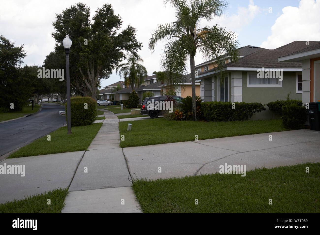 Fußweg Bürgersteig durch gated community und konkrete Einfahrt in Kissimmee während bedeckt stürmischer Sommertag Florida USA Vereinigte Staaten von Amerika Stockfoto