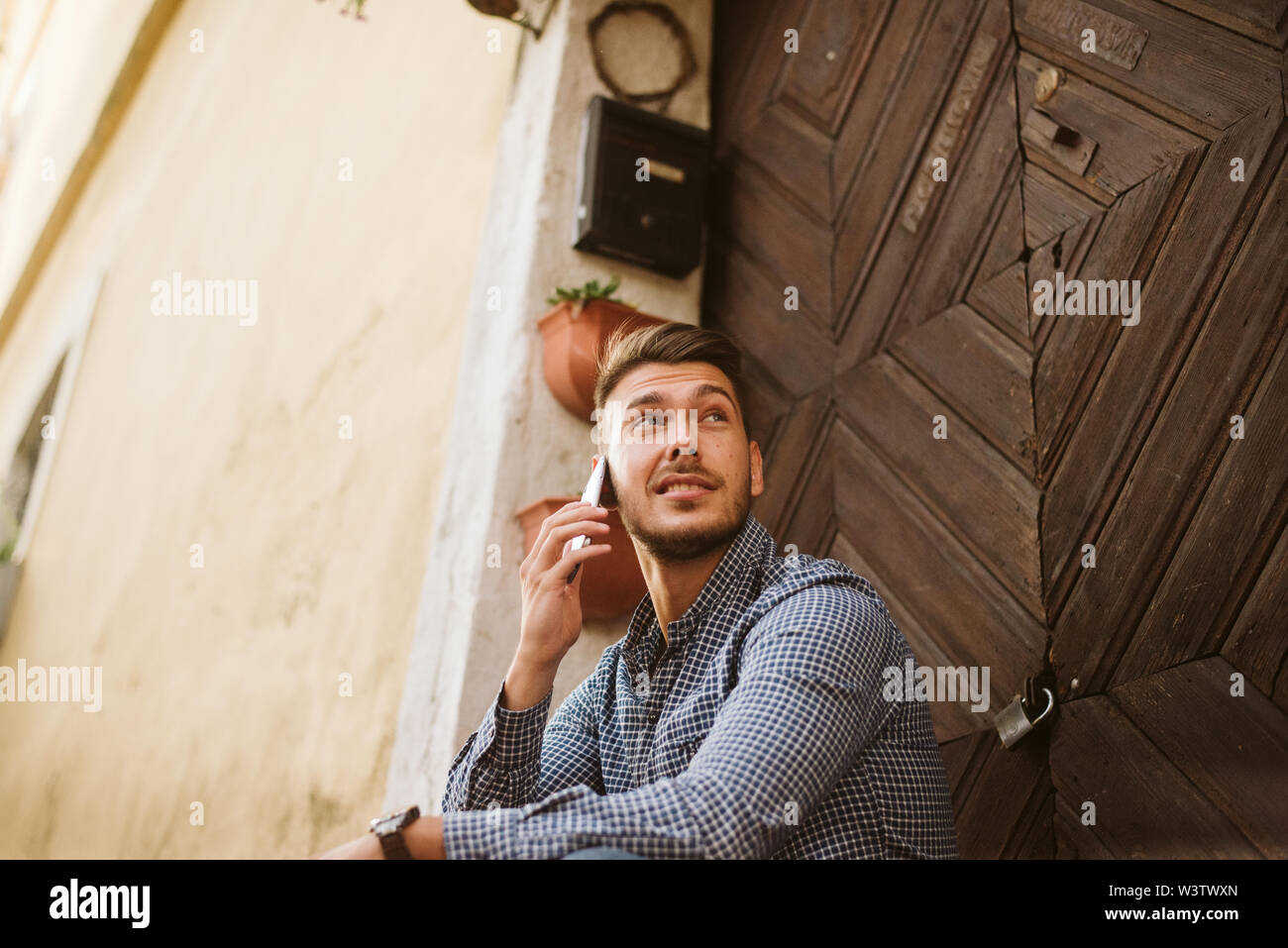 Junge Mann in einem Café sitzen, Kaffee trinken und reden, und auf einem Mobiltelefon Stockfoto