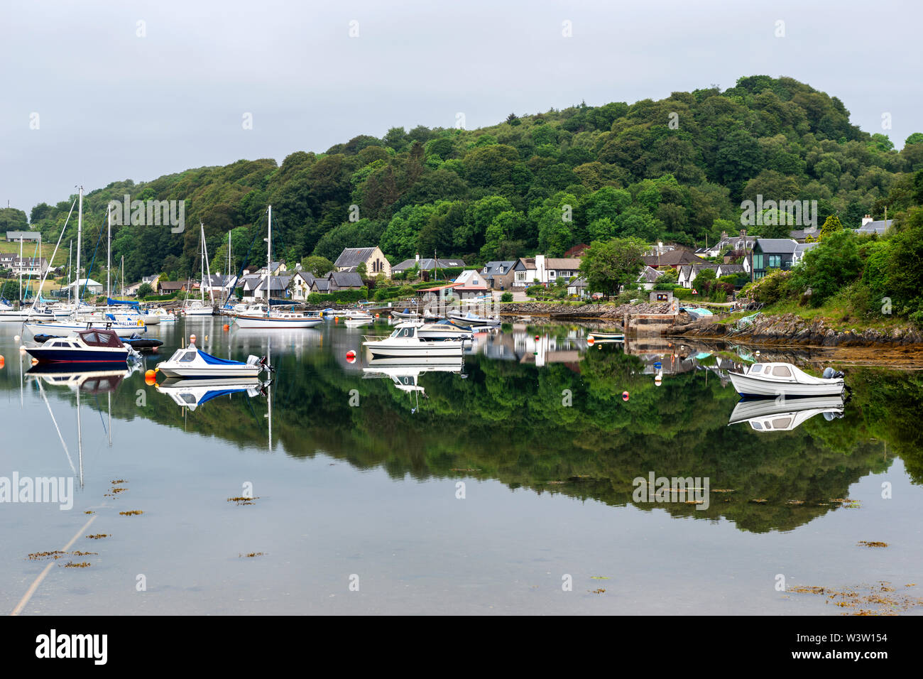 Am frühen Morgen bunte Reflexionen der Boote vor Anker am Loch Sween im malerischen Fischerdorf Tayvallich in Argyle und Bute, Schottland, Großbritannien Stockfoto