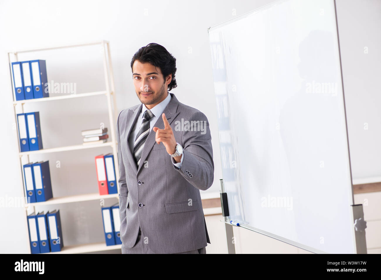 Theyoung gut aussehender Geschäftsmann vor Whiteboard Stockfoto