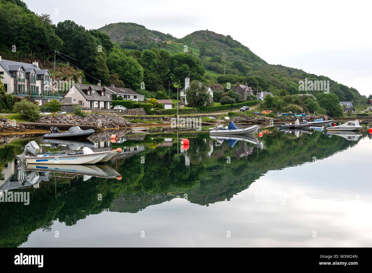 Am frühen Morgen bunte Reflexionen der Boote vor Anker am Loch Sween im malerischen Fischerdorf Tayvallich in Argyle und Bute, Schottland, Großbritannien Stockfoto