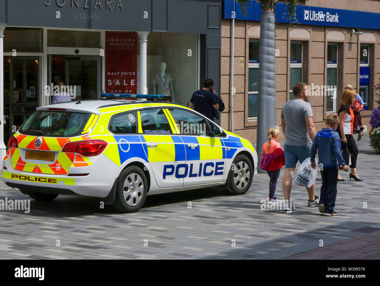PSNI geparkten Polizeiwagen außerhalb des Shops in einer Fußgängerzone mit Menschen zu Fuß vorbei an einem sonnigen Nachmittag in Lisburn, Nordirland. Redaktionelle Verwendung onl Stockfoto
