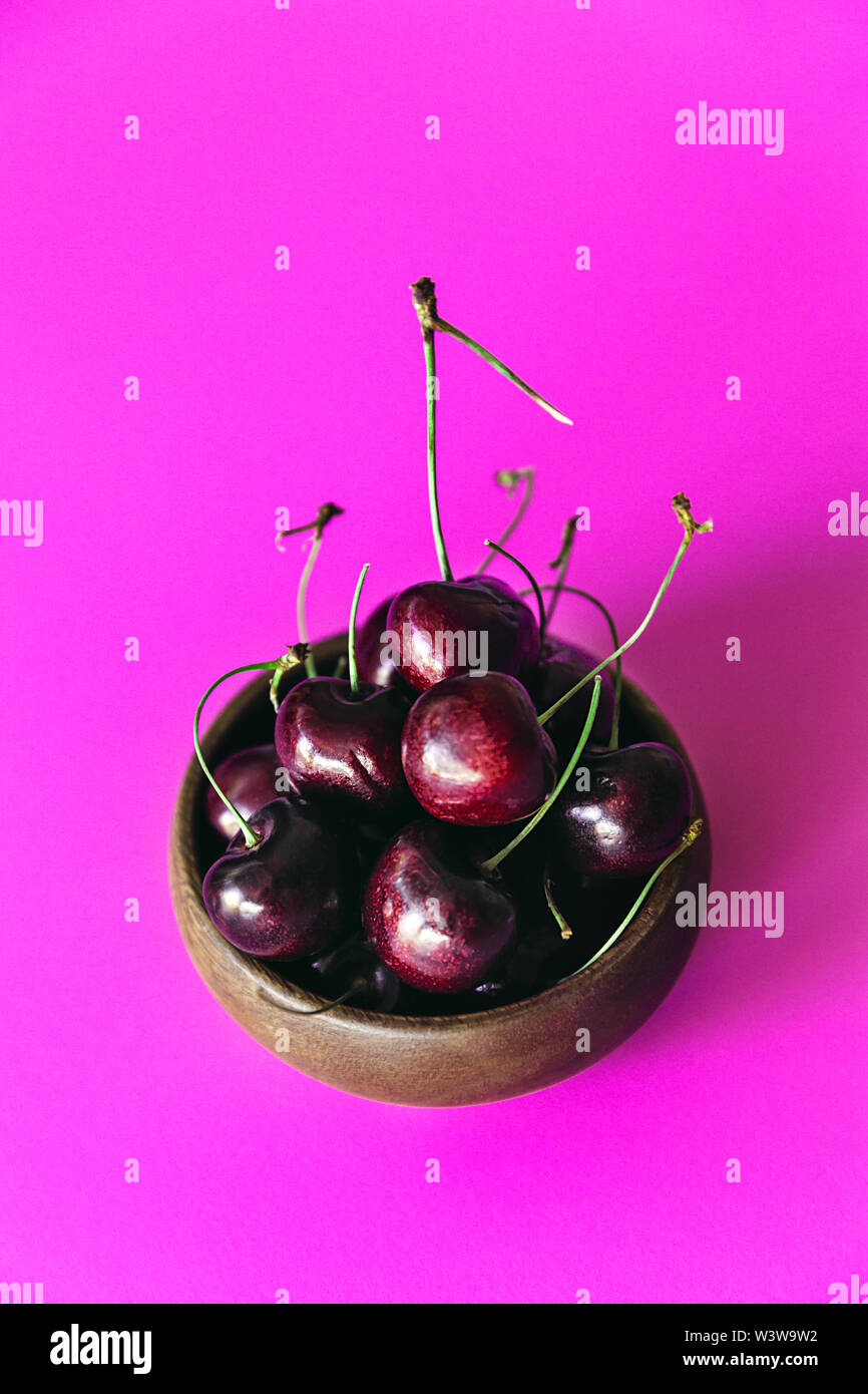 Frische Kirschen in eine kleine Schüssel auf einem hellen rosa Hintergrund, Ansicht von oben - Bild Stockfoto