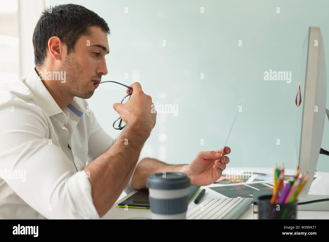 Männliche Graphic Designer bei Fotos am Schreibtisch im Büro suchen Stockfoto