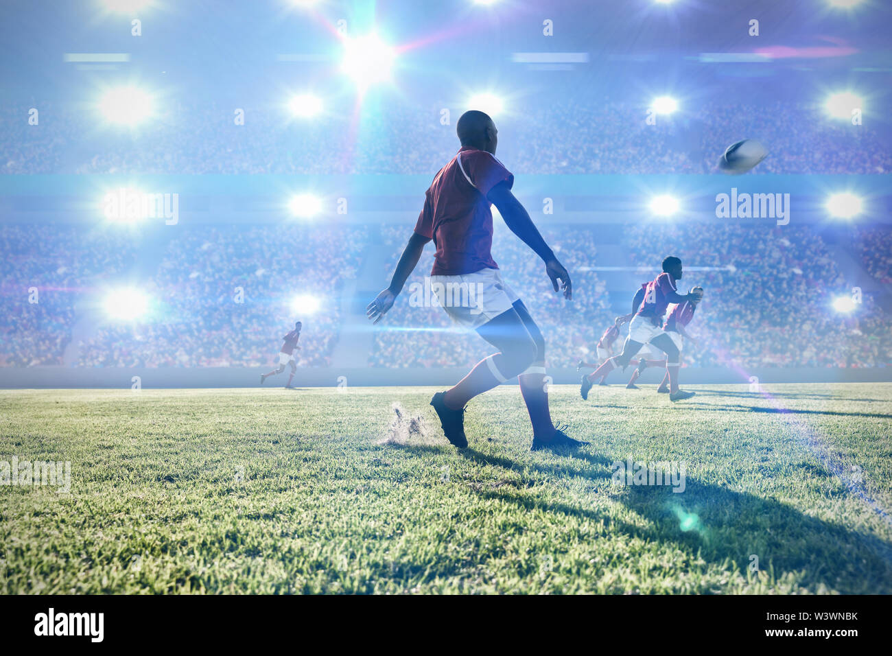 Das zusammengesetzte Bild im Rugby Spieler kicken den Ball mit Teamkollegen auf dem Feld. Stockfoto