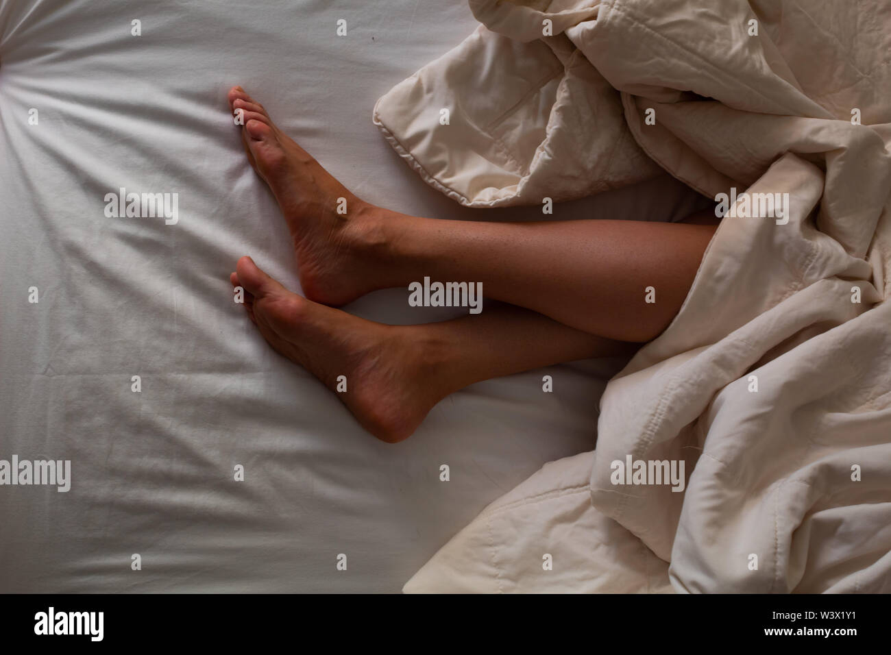 Hispanic Frau im Hotel Bed ruht, bedeckt mit einer Decke (unterschiedliche Fuß und Full Body Shots) die Idee der ​​Rest zu konzipieren Stockfoto