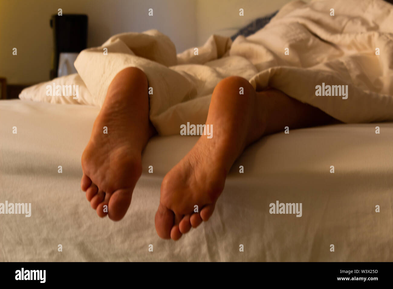 Hispanic Frau im Hotel Bed ruht, bedeckt mit einer Decke (unterschiedliche Fuß und Full Body Shots) die Idee der ​​Rest zu konzipieren Stockfoto
