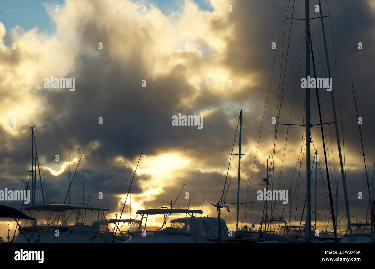 Sonne bricht dramatisch durch Verdunkelung Regenwolken über Yachten in der Marina an der Küste von Western Australia Stockfoto
