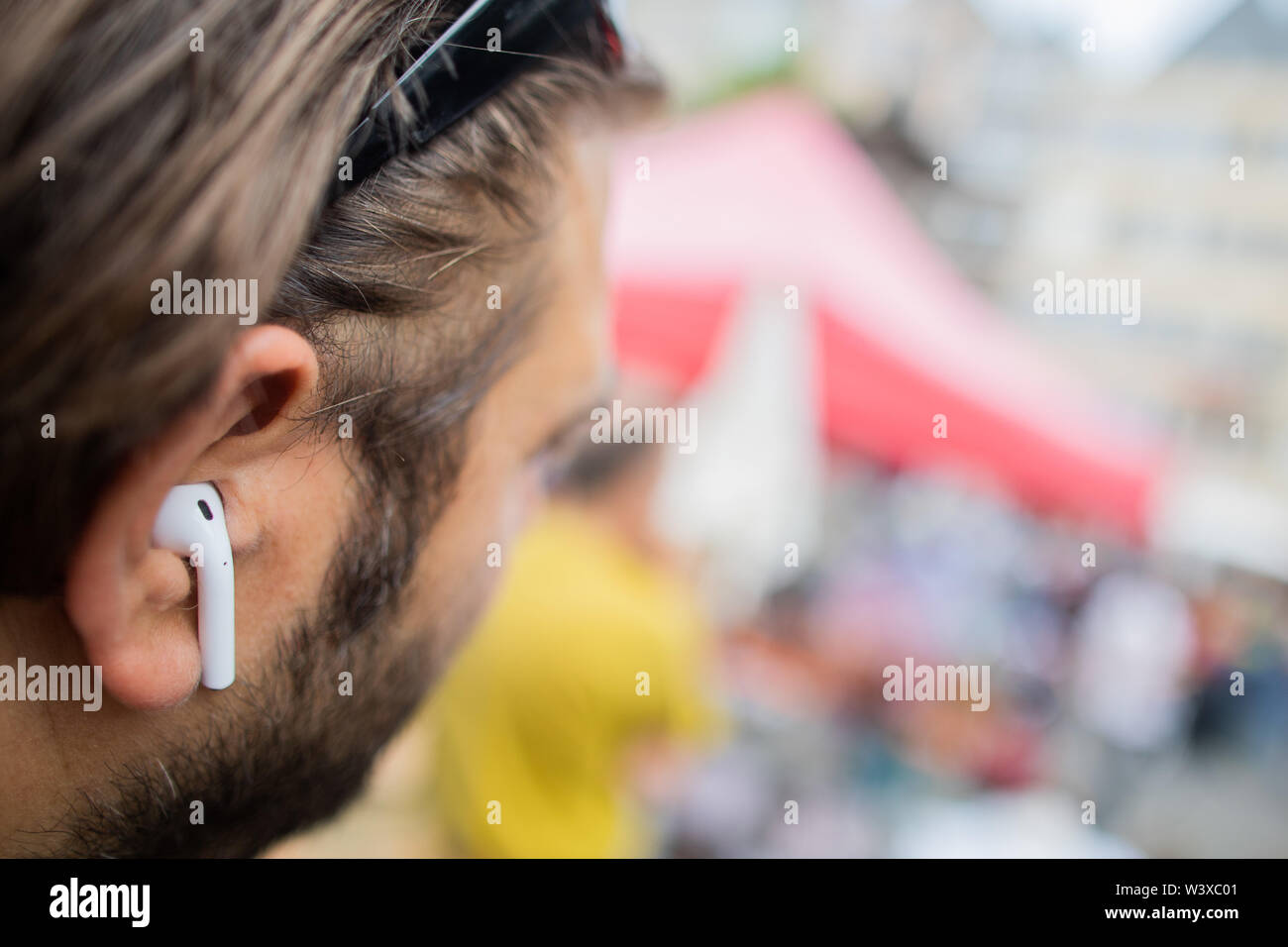 Köln, Deutschland. 12. Juli, 2019. Ein Mann trägt AirPods, drahtlose  Kopfhörer von Apple in seinen Ohren. Einkaufsmöglichkeiten, Bahn, Freunde  treffen oder herauf Kinder aus der Schule - mehr und mehr Menschen alles