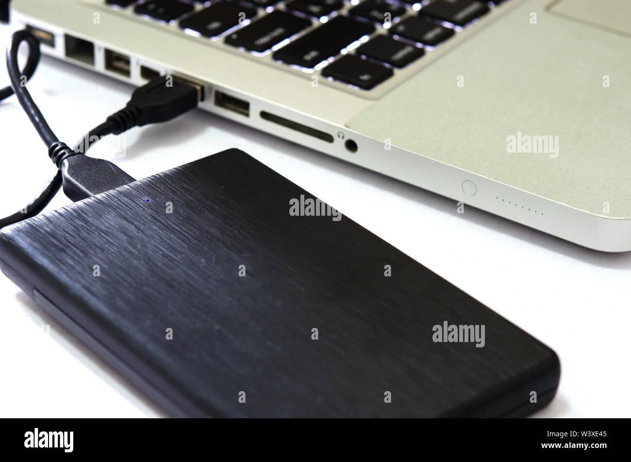 Externe Festplatte an den Laptop auf den weißen Hintergrund. Stockfoto