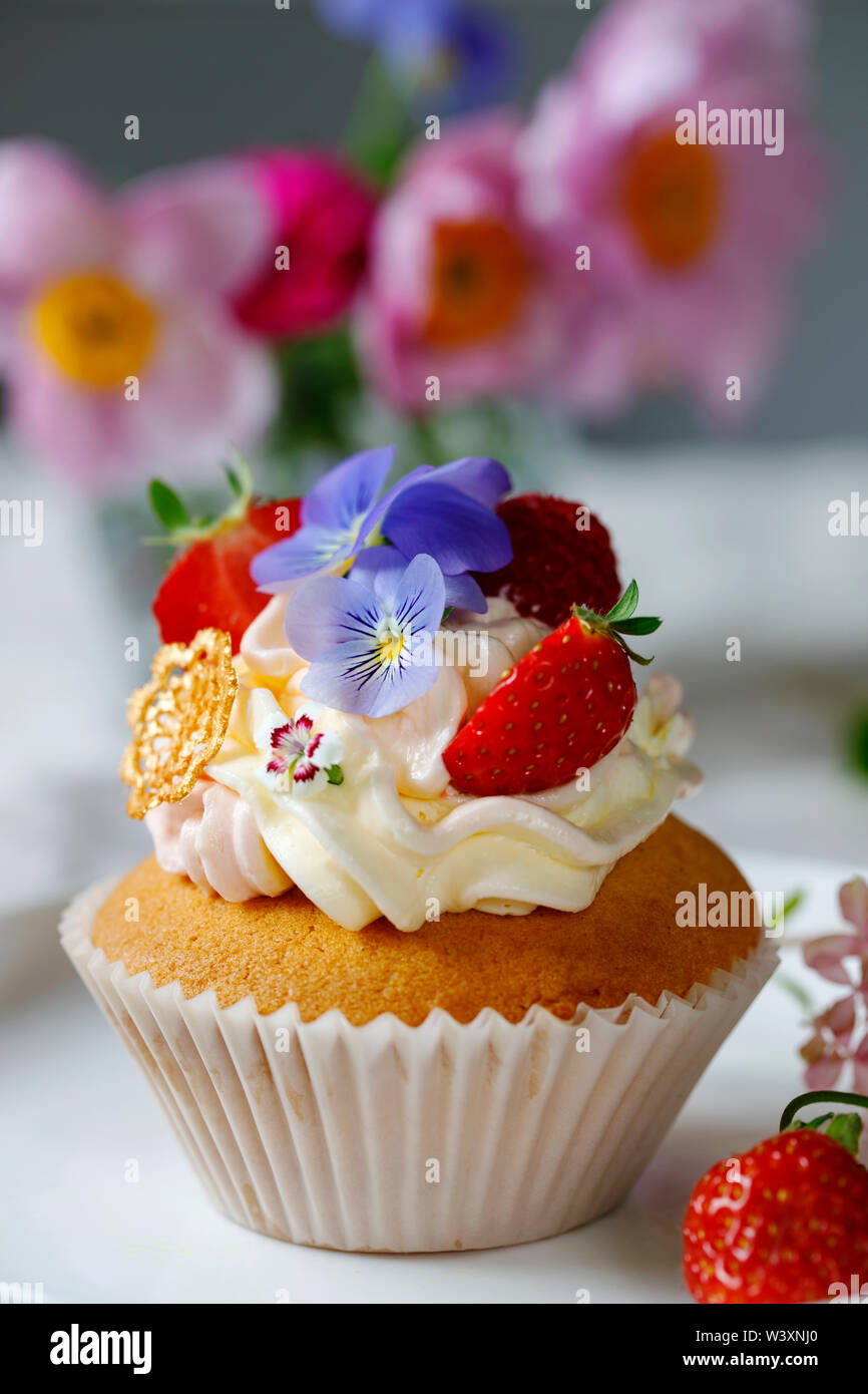 Cupcake mit buttercream, Früchte und Blumen dekoriert Stockfoto