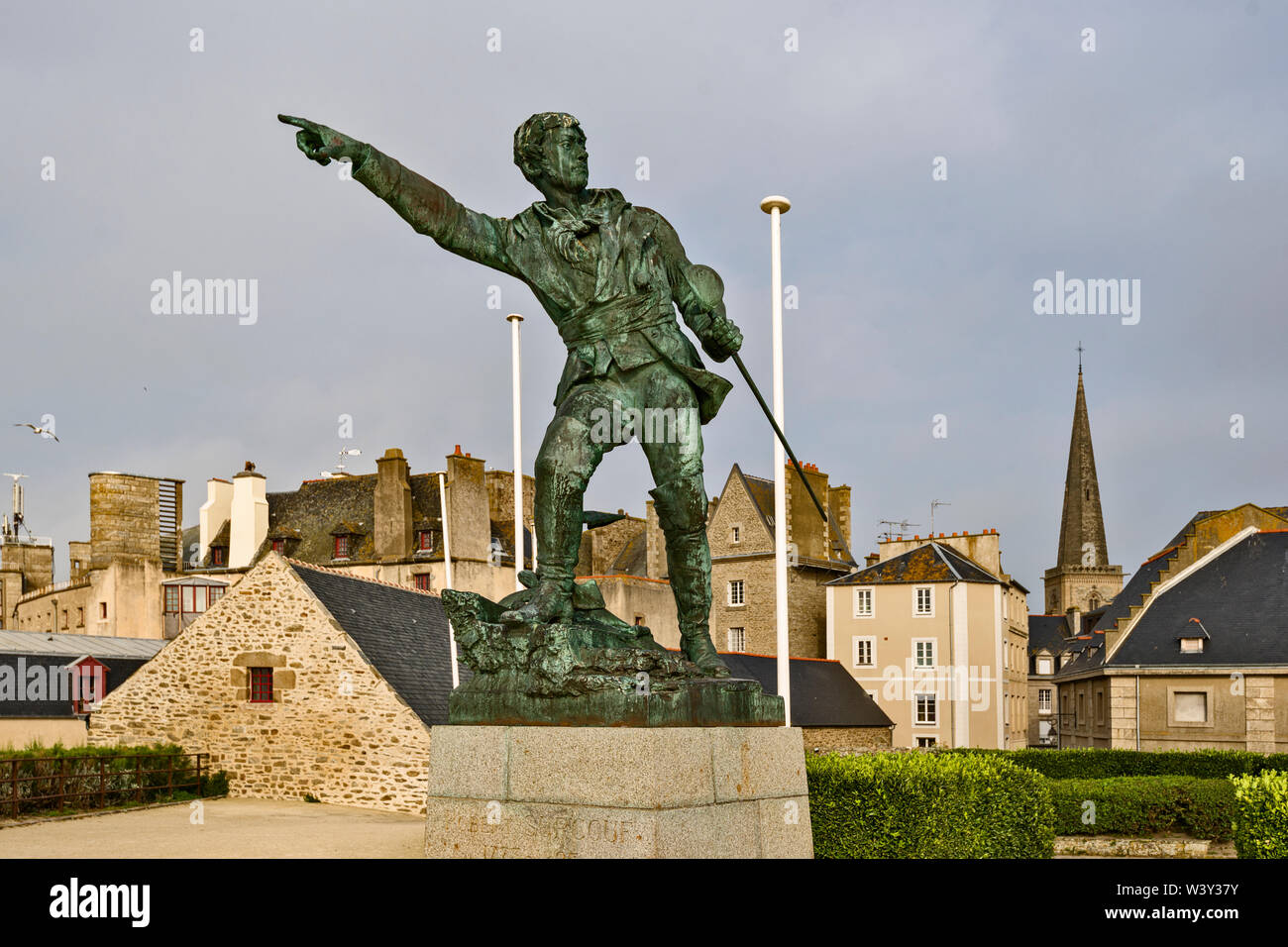 Statue zum Gedenken an Sailor Robert Surcouf, war der französische Privatfahrer mit der ummauerten Stadt im Hintergrund in Saint Malo, Frankreich Stockfoto