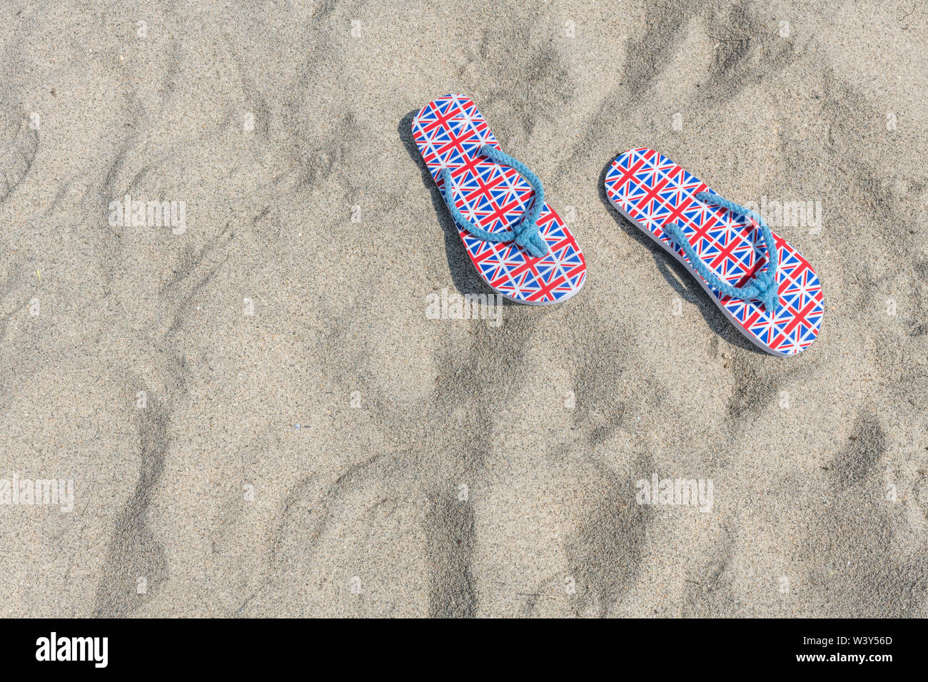 Flipflops mit GB-Flagge / Union Jack am Sandstrand - für 2021 Aufenthalte in Großbritannien, Urlaub zu Hause, Aufenthalt in Cornwall, Badeurlaub, Flip-Flop-Schuhe. Stockfoto