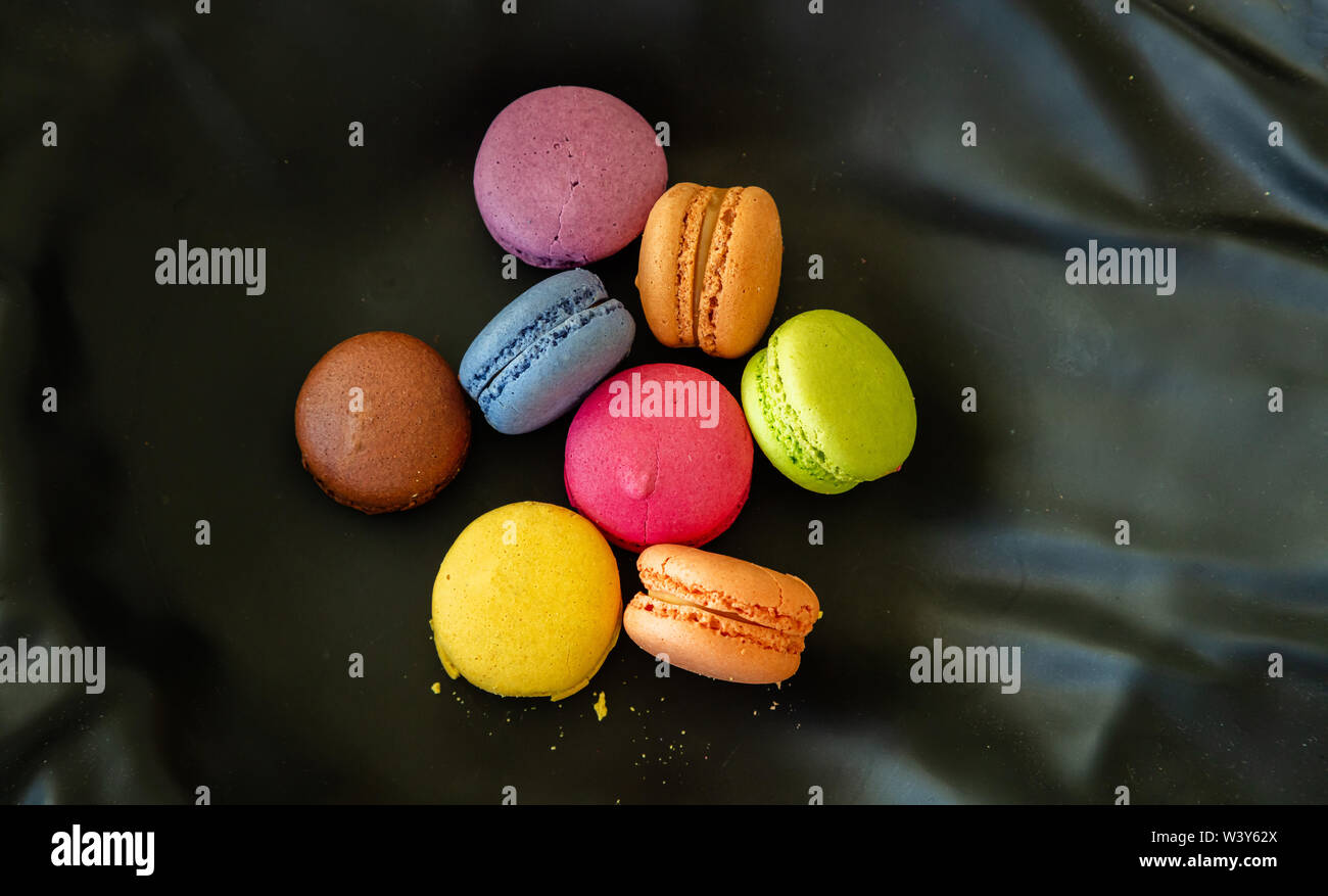 Macarons Pastellfarben mit Schokoladencreme auf schwarzem Hintergrund, Ansicht mit Details, Ansicht von oben schließen Stockfoto