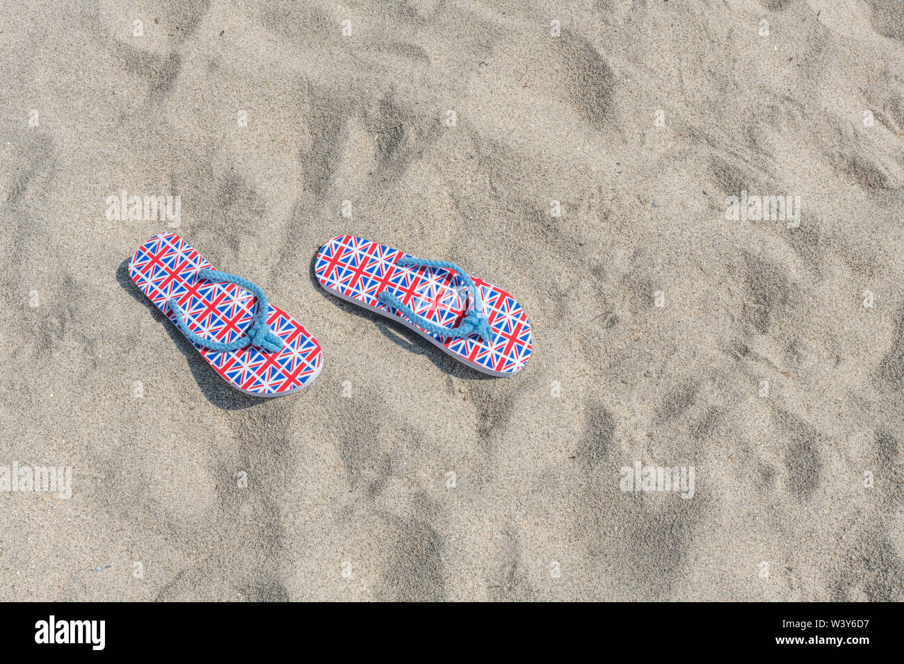 Flipflops mit GB-Flagge / Union Jack am Sandstrand - für 2021 Aufenthalte in Großbritannien, Urlaub zu Hause, Aufenthalt in Cornwall, Badeurlaub, Flip-Flop-Schuhe. Stockfoto