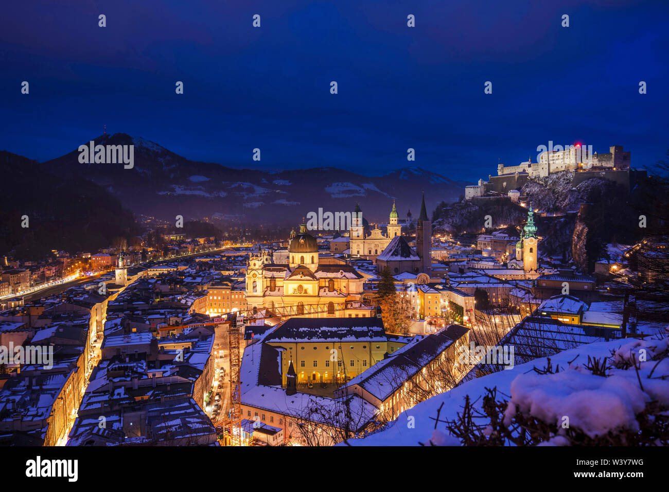 Blick auf die Stadt Salzburg bei Nacht an einem Winterabend mit den Dächern mit Schnee und der Festung Hohensalzburg überdachten erhöhten Stockfoto