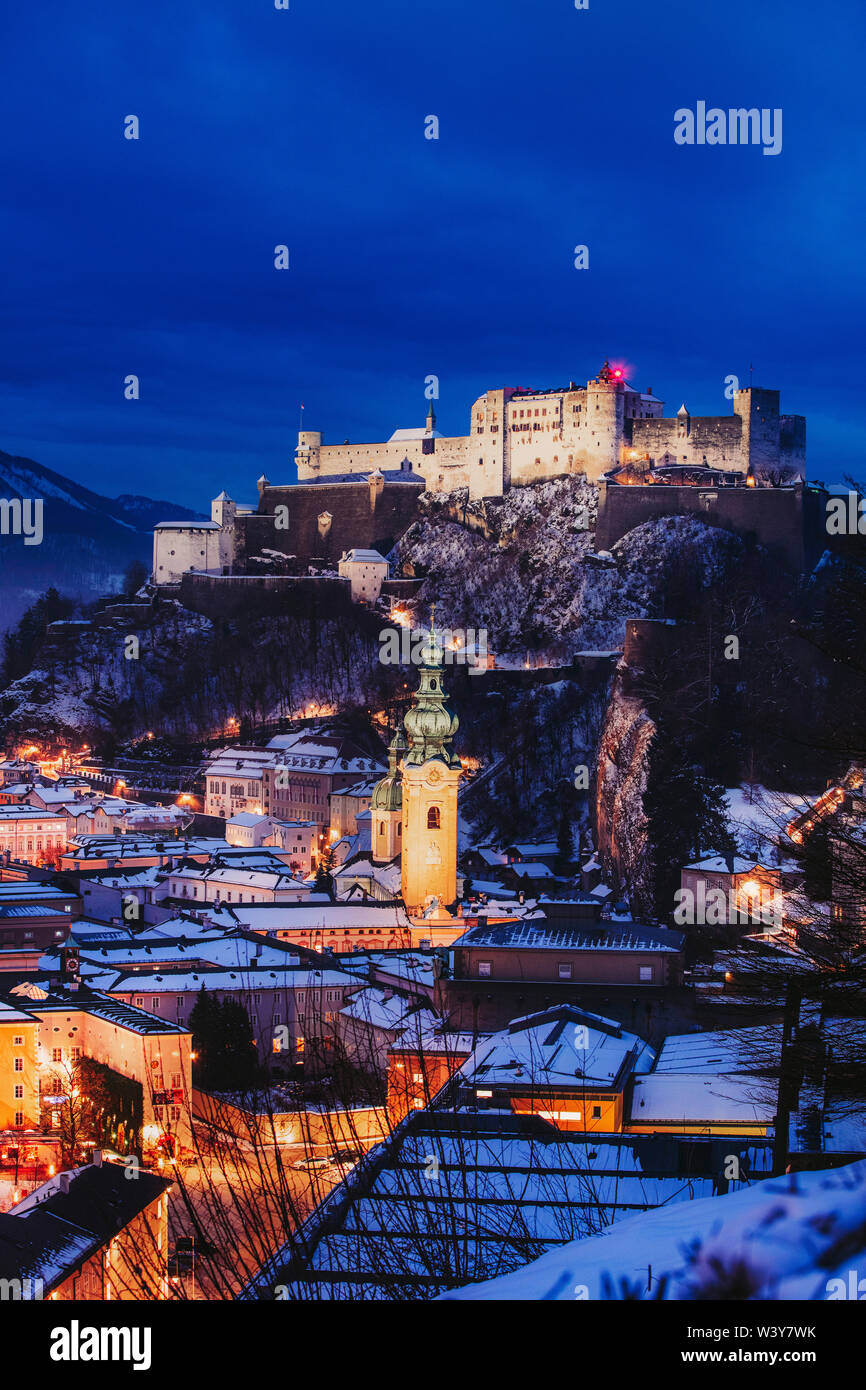 Blick auf die Stadt Salzburg bei Nacht an einem Winterabend mit den Dächern mit Schnee und der Festung Hohensalzburg überdachten erhöhten Stockfoto