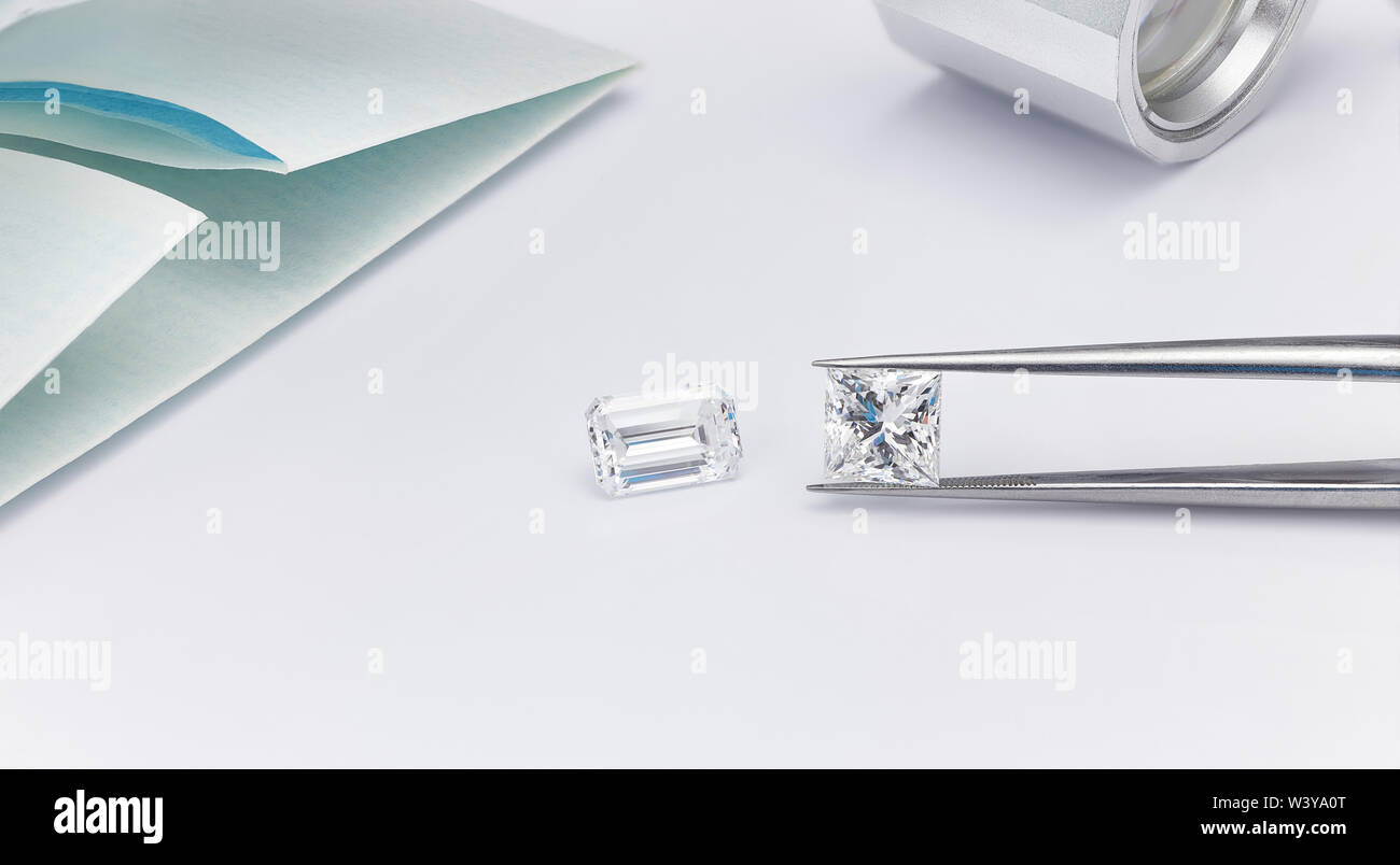 Große Diamanten Princess Cut und Emerald Cut Diamond mit Diamant Paket- und Diamond Pinzette mit Lupe auf weißem Hintergrund Stockfoto