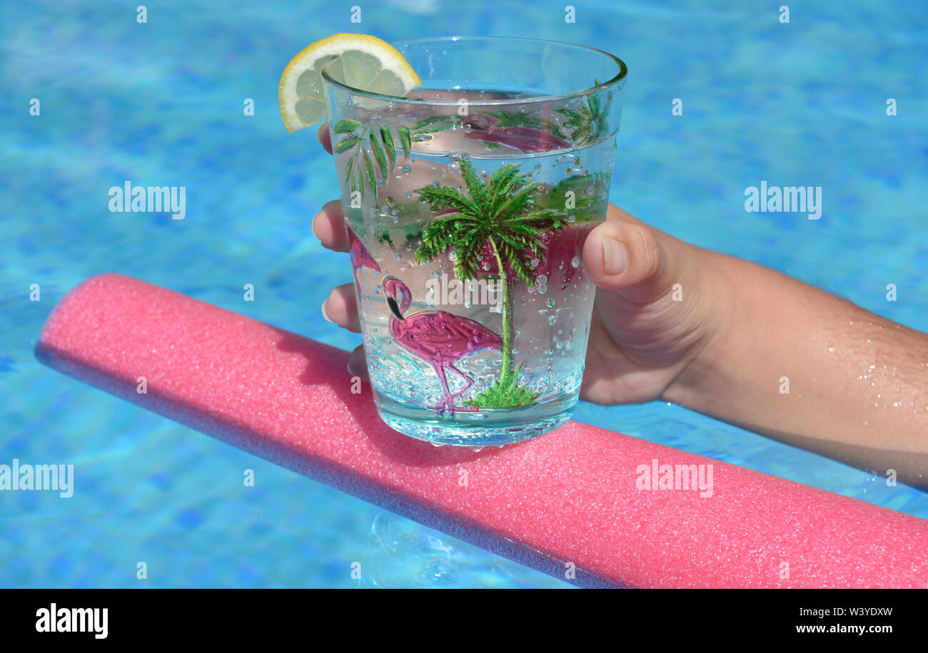 Junge Frau mit einem kühlen Getränk schwimmt auf einem Pool Nudel in einem Schwimmbad. Sommer vibes, cool Bleiben, Spaß haben. Stockfoto