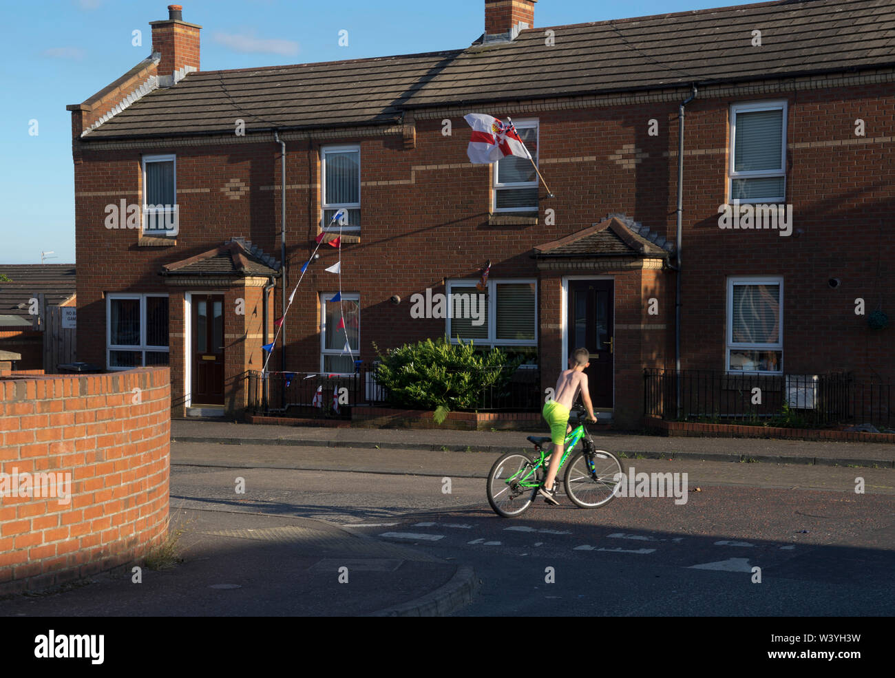 Kind auf einem Fahrrad mit loyalistischen Fahnen und Banner im Hintergrund in der Shankhill Bereich von Belfast, Nordirland Stockfoto