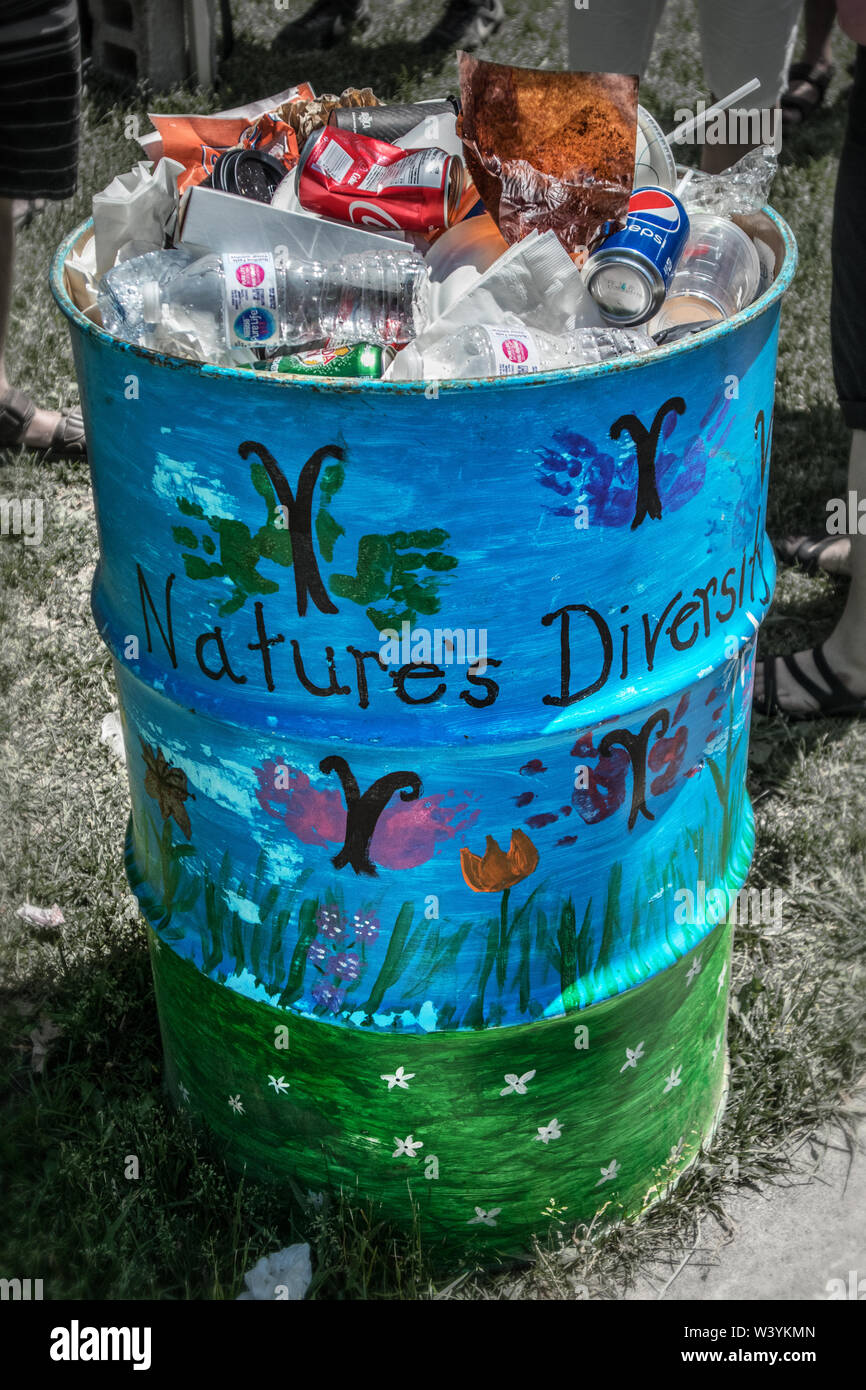 Ein großes Metall Mülleimer im Park wird von Kindern unter dem Thema Natur für Vielfalt eingerichtet. Der Papierkorb ist voll von "Abfall der Vielfalt". Stockfoto